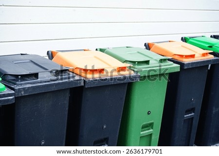 A row of garbage bins with different colored lids for separate waste collection: plastic, paper, glass, organic waste, and general trash. Concept of recycling and eco-friendly waste management.