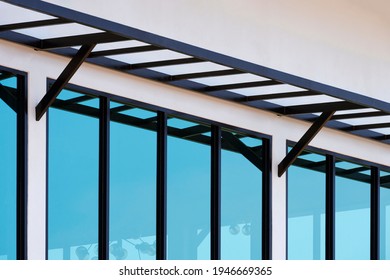 Row Of Glass Windows With Steel Awning Structure On White Cement Wall Of Incomplete Modern House In Construction Site, Low Angle And Diagonal View