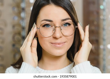 Row of glasses at an opticians. Eyeglasses shop. Stand with glasses in the store of optics. Woman chooses spectacles. Eyesight correction.