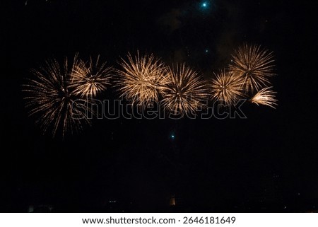 Row of golden fireworks exploding in the night sky above a dark cityscape. Symmetrical bursts create an elegant and festive atmosphere, perfect for holiday or celebration themes. Vietnam