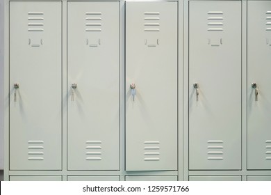 A row of grey metal school lockers with keys in the doors