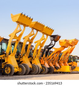 Row Of Heavy Construction Excavator Machine  Against Blue Sky In A Construction Site.