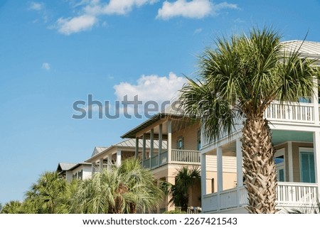 Row of houses with balconies with palm trees view at the front in Destin, Florida. There are palm trees at the front of the houses under the sky.
