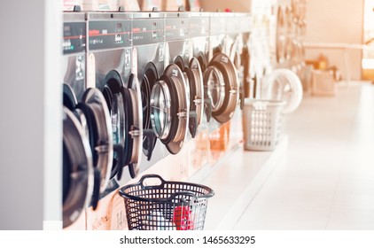 Row of industrial laundry machines in laundromat  in a public laundromat, with laundry in a basket , Thailand
