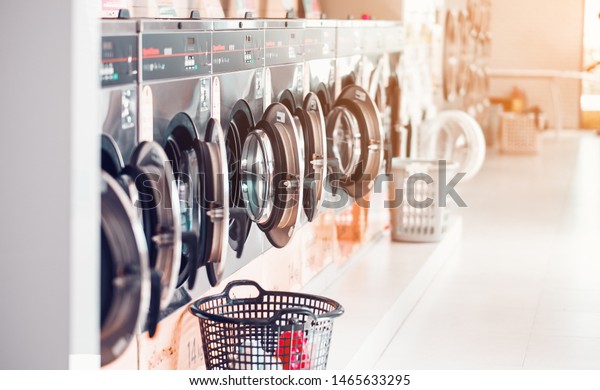Row of\
industrial laundry machines in laundromat  in a public laundromat,\
with laundry in a basket ,\
\
Thailand