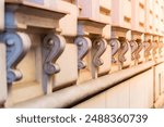 A row of intricate, decorative brackets on a building facade, showcasing ornate craftsmanship and architectural detail. The warm tones and soft lighting create a sense of classic elegance