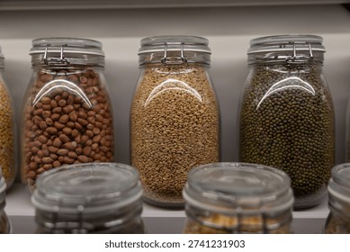 A row of jars filled with different types of nuts and grains. The jars are lined up on a shelf, with some of them being filled to the brim and others only partially filled. The variety of nuts