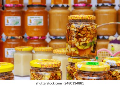 A row of jars filled with various types of food, walnuts in honey