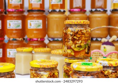 A row of jars filled with various types of food, walnuts in honey