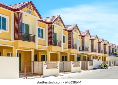 The row of just finished new yellow townhouses, Modern village buildings with blue sky, Concept of buying a house vs renting an apartment.