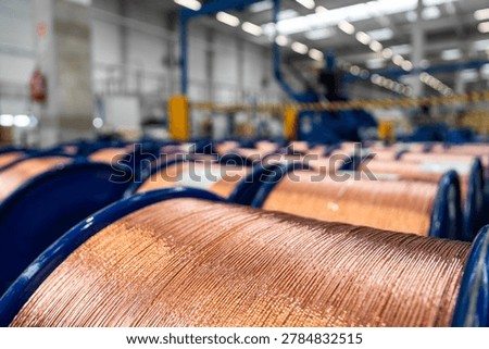 Row of large blue spools with copper wire inside a modern industrial plant