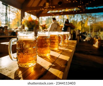 Row of larges mugs with Beer on a table in a pub, bar or October festival grounds. Concept of beer with friends and German beer festival. Shallow field of view.