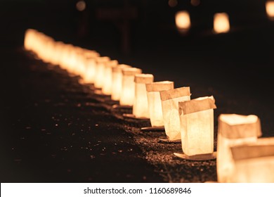 Row, line of Christmas Eve candle lights, lanterns in paper bags at night along road, street, path illuminated by houses in residential neighborhood in Virginia
