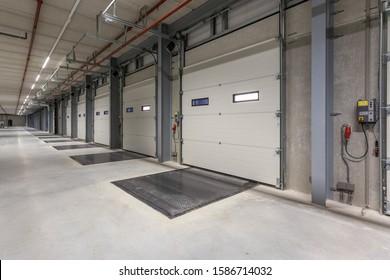 A Row Of Loading Docks In A Warehouse With Turned-on Lights On The Ceiling