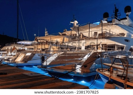 A row of luxury yachts docked in the marina at night.