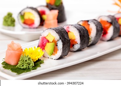 Row of maki sushi  with ginger and wasabi on plate