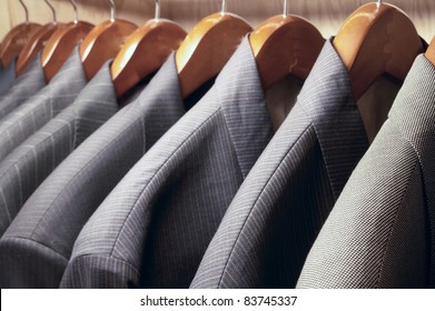 Row Of Men's Suit Jackets Hanging In Closet