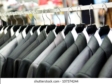 Row of men's suits hanging in closet. - Powered by Shutterstock