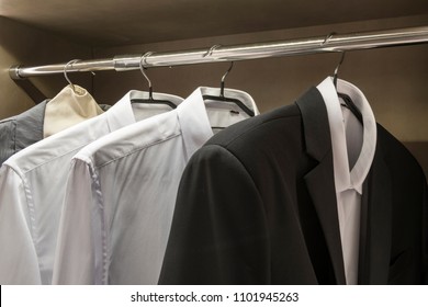 Row Of Men's Suits Hanging In Closet. 