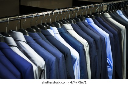 Row Of Men's Suits Hanging In Closet.