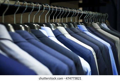 Row Of Men's Suits Hanging In Closet.