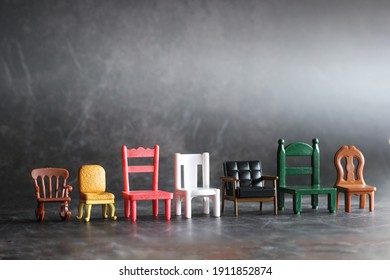 Row Of Miniature Chairs In Various Style In Vintage Tone Background. Doll Furniture House On The Black Floor.