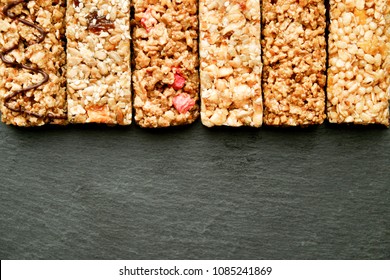 Row of mixed gluten free granola cereal energy bar with dried fruit & various nuts, gray concrete background. Healthy vegan super food, fitness dieting snack for sporty lifestyle. Top view, copy space - Powered by Shutterstock