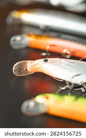 Row of modern spinning lures with sharp treble hooks on a black surface
