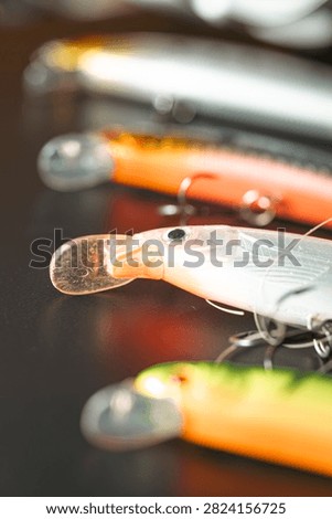 Row of modern spinning lures with sharp treble hooks on a black surface