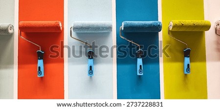 A row of multicolored paint rollers mounted on vertical panels. Concept for decorating, construction, renovation, home improvement, and DIY creative projects