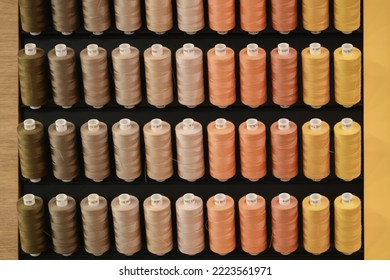 A row of multi-colored thread spools in brown orange yellow tones