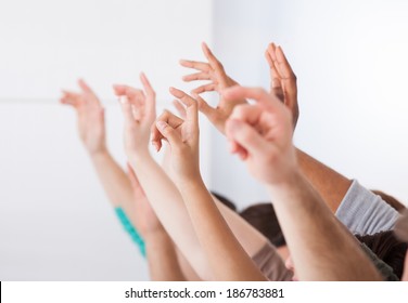 Row of multiethnic college students raising hands in classroom