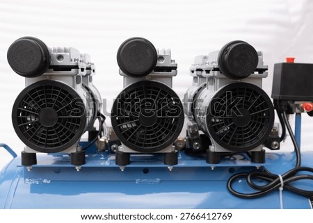 Row of multiple oilless air compressor motors with black cooling fans and intake filters, high-capacity industrial pneumatic system for silent and clean air production.