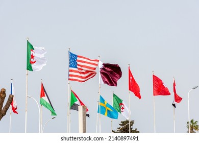 A row of national flags of several countries waving against a clean blue sky. Close up. Worldwide event concept.