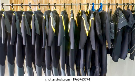 A row of neoprene diving wetsuits hanging on a rack in a resort dive shop in the Philippines.