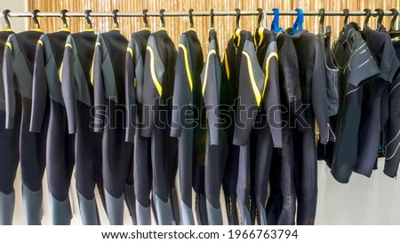 A row of neoprene diving wetsuits hanging on a rack in a resort dive shop in the Philippines. 商業照片 © 