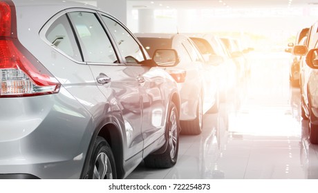 A row of new cars parked at a car dealership stock. New cars in the showroom for customers to view and buy. - Shutterstock ID 722254873