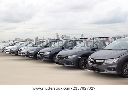 A row of new cars parked at a car dealership stock