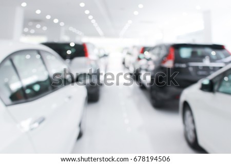 A row of new cars parked at a car dealership stock blurry