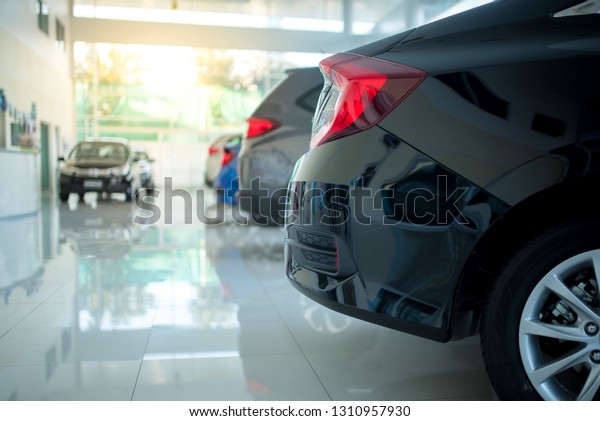 A row of new cars\
parked at a car dealership stock. New cars in the showroom for\
customers to view and buy