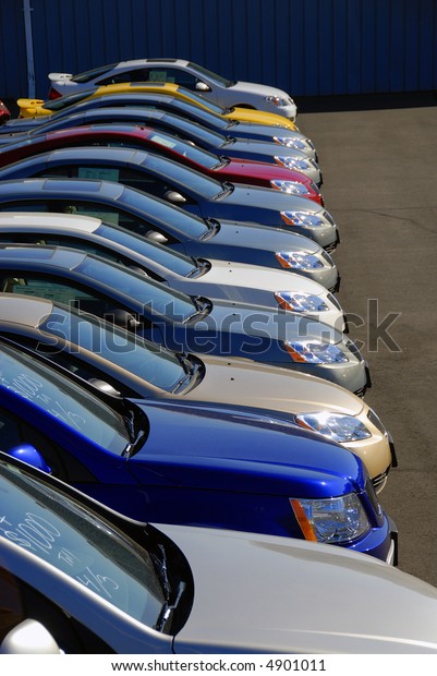 A row of new\
cars parked at a car dealer\
shop
