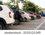 A row of new colorful vehicles on the parking. A line of used cars and trucks for sale