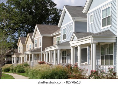 Row of newly constructed townhomes in a sidewalk neighborhood.
