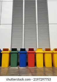 Row Of Old Green,red, Blue And Yellow Trash Bin Font Of The Wall.