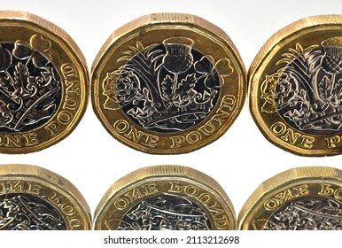 Row Of One Pound Coins Standing On Edge Reflected In A Mirror. No People.