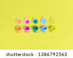 Row of open paint pots isolated on a yellow background. Top view with copy space