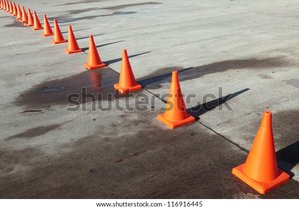 A row of\
orange traffic cones set on the\
road