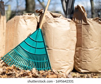 a row of paper leaf composting bags with a leaf rake leaning on them - Shutterstock ID 1695642331
