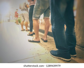 Row of People in queue for waiting something. Back of man and woman orderly in line. Close up legs of people