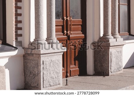 A row of pillars standing in front of a large building, perhaps an entrance or facade.